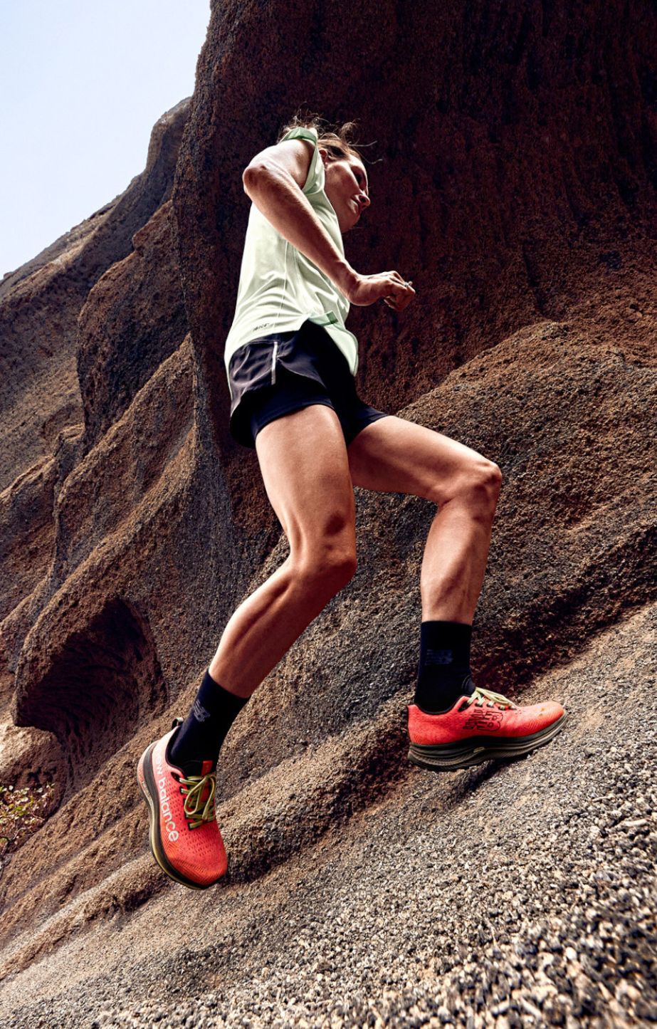 woman running on a rock wearing New Balance Trail runners and performance clothes
